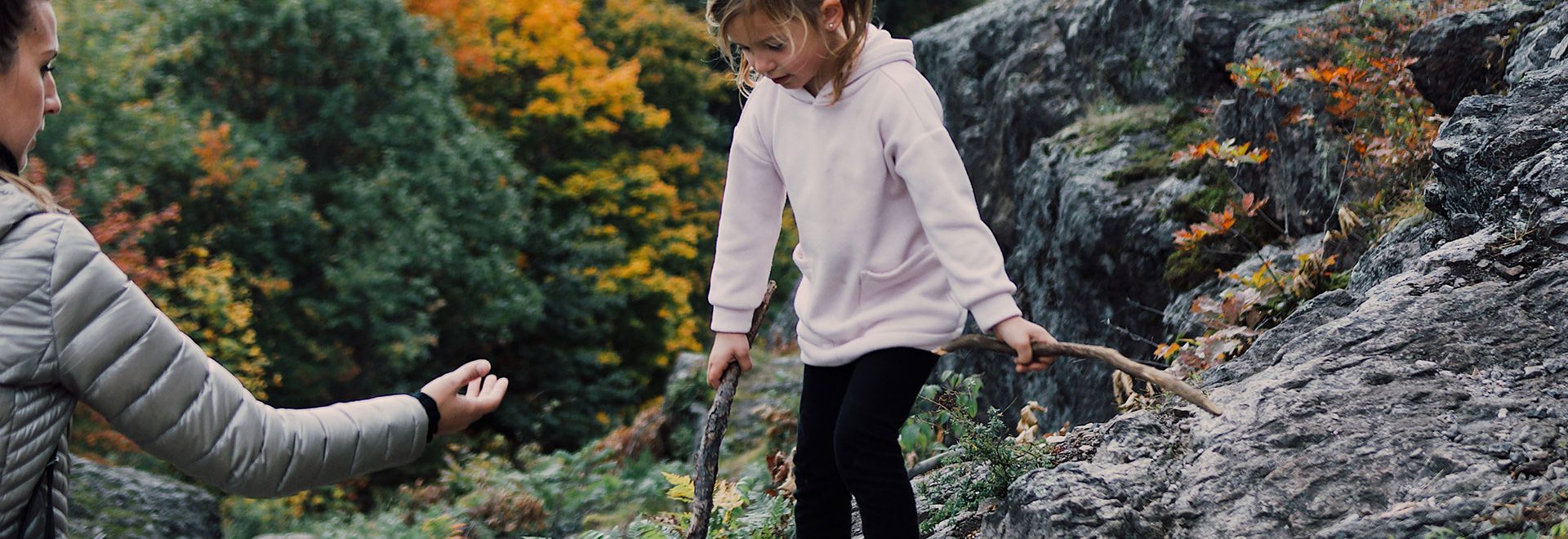 Girl climbing on rocky trail with her mother's help